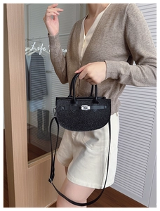 Detailed view of black glitter crescent saddle bag with silver twist lock on model