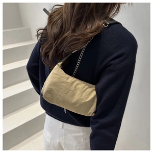 Detail view of khaki nylon underarm bag with leather and silver chain strap