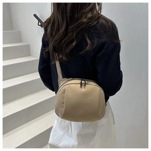 Detail of khaki shell-shaped crossbody bag with dual zippers and ergonomic wide strap