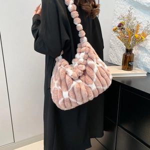 Detail of plush pink and white checkered tote bag with fuzzy ball strap and soft texture