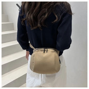 Close-up of light beige nylon waist bag with black zippers and side logo tag detail
