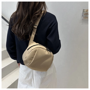 Rear view of khaki nylon crossbody sling bag worn over a casual sports outfit