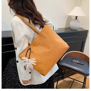 Detailansicht der großen orangen Tragetasche mit weißem Blumenanhänger am Schultergurt
