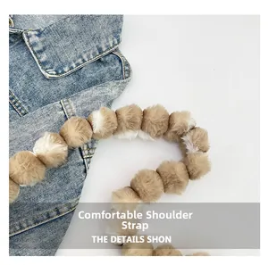 Detail of plush faux fur ball shoulder strap in brown and white stripes on denim