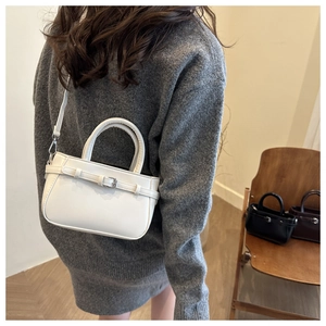 Minimalist white leather bucket bag detail with silver buckle and detachable shoulder strap