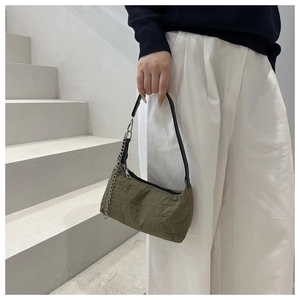 Detailed view of olive green shoulder bag with crinkled texture and silver metal chain