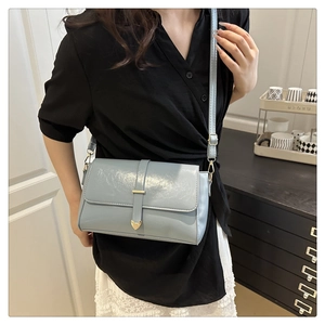 Vue détaillée du sac bandoulière en cuir verni bleu clair avec fermoir doré en cœur