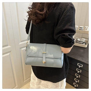 Détail du sac à bandoulière bleu clair avec fermoir cœur doré sur un mannequin