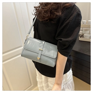 Détail du sac bandoulière bleu clair avec fermoir coeur doré et texture cuir mat