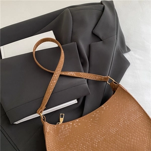 Brown snake-print embossed underarm shoulder bag with gold zipper on a gray blazer
