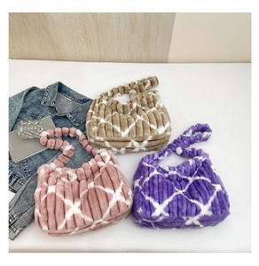 Detail of plush quilted tote bags in pink, khaki, and purple on a white display