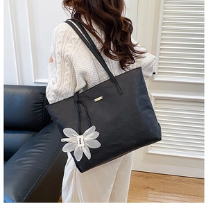 Close-up of large black tote bag with wrinkled texture and white daisy flower charm