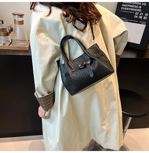 Détail du sac à main noir en cuir tressé avec bandoulière réglable et boucle décorative