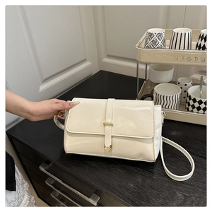 Gros plan d'un sac à bandoulière vintage crème avec cuir brillant et boucle cœur dorée