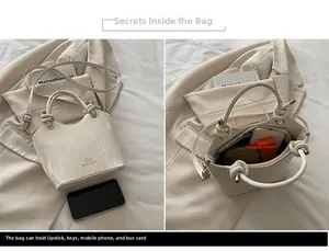 Vue détaillée du sac seau beige avec texture marbrée, poignée en métal noué et intérieur spacieux