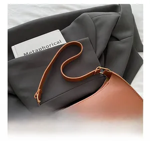 Detail of a brown leather shoulder bag featuring golden rings and elegant stitching