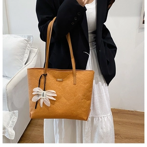 Detail of ginger tote bag featuring pleated texture and a floral charm with FUOR logo