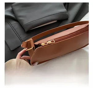 Close-up of vintage brown leather bag featuring a smooth gold metal zipper and slim strap