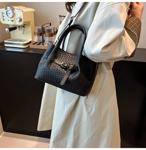 Détail d'un sac à main noir tressé avec boucle métallique et doubles poignées pour femme