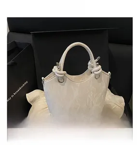Détail du sac seau blanc à motif marbré avec poignée à nœud et logo doré