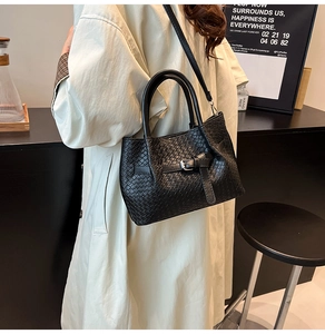 Side view of a black woven bucket bag with silver buckle and leather strap on a model