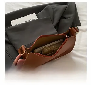 Internal view of minimalist caramel leather shoulder bag showing phone and wallet storage