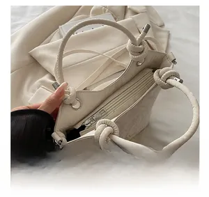 Détails du zip argenté et de la texture florale gaufrée sur le sac bandoulière ivoire