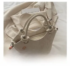 Détail d'un sac à main crème avec poignée en corde nouée et texture marbrée