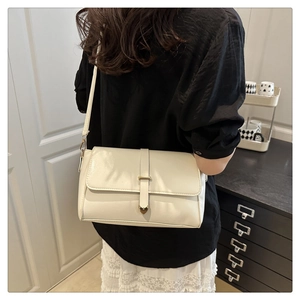 Modèle portant un sac bandoulière crème avec boucle en cœur dans un décor intérieur minimal