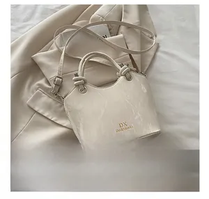 Détail du sac seau à motif marbre blanc avec logo DX sur une veste de costume beige