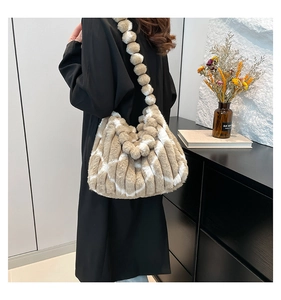 Detail of plush striped shoulder bag featuring unique round faux fur ball strap design