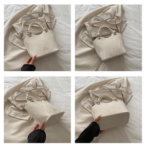 Détails de la texture marbrée et du logo doré sur ce sac seau blanc élégant pour femme