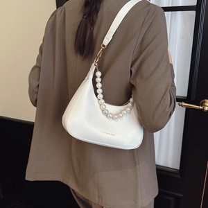 Fashionable white crescent shoulder bag with pearl chain strap worn by a model