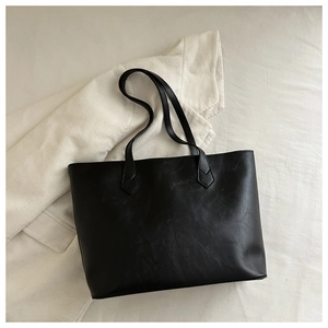 Gros plan sur un sac cabas vintage noir avec texture cuir et doubles poignées minimalistes