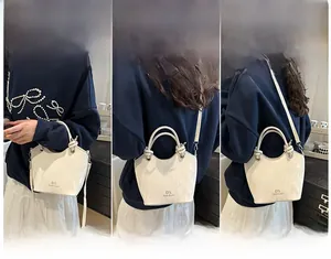 Sac seau en cuir texturé crème en trois styles : à main, en bandoulière et porté à l'épaule