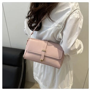 Vue détaillée du sac à bandoulière rose avec boucle cœur dorée sur le rabat texturé
