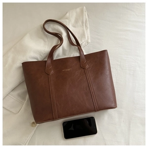 Détails du sac fourre-tout marron grainé avec logo doré et téléphone de référence