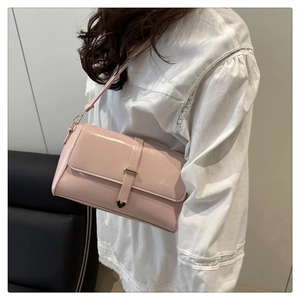 Détail du sac bandoulière en cuir verni rose clair avec boucle métallique en forme de cœur
