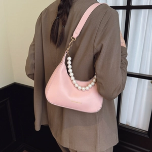 Pink half-moon underarm bag with pearl chain shown as styled on a model's shoulder