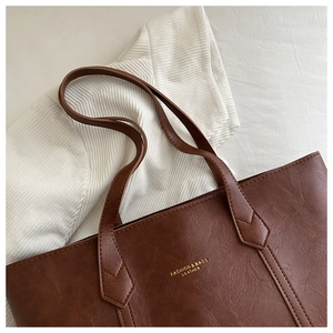 Détail du sac cabas marron foncé avec texture cuir grainée et logo doré embossé