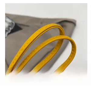 Dettaglio della comoda tracolla in ecopelle giallo brillante con cuciture curate
