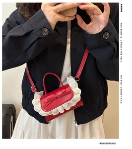 Close-up of red mini crossbody bag with a delicate bow and white heart lace trim detail