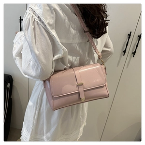 Borsa a spalla in pelle verniciata rosa con dettagli dorati in un contesto di moda
