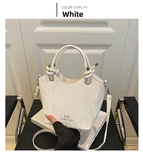 Détail du sac seau blanc avec poignées nouées et logo DX imprimé en doré chic