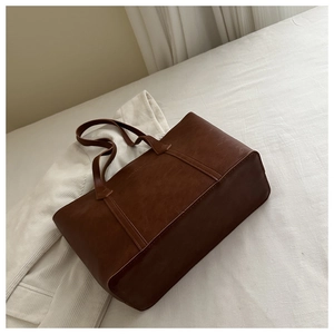 Texture détaillée d'un grand sac cabas marron en similicuir sur un fond blanc épuré