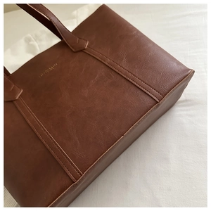 Gros plan d'un sac cabas marron montrant le grain de cuir et l'inscription dorée