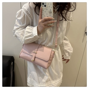 Détail d'un sac à bandoulière rose avec fermoir coeur doré sur une robe blanche