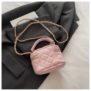 Detail of pink quilted vanity bag with gold chain strap on a black suit blazer