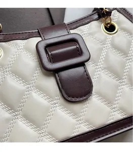 Dettaglio borsa trapuntata beige con finiture in pelle marrone e anelli in metallo oro