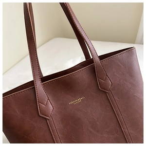 Vue détaillée du cuir grainé marron foncé avec lettrage doré sur un sac à main cabas